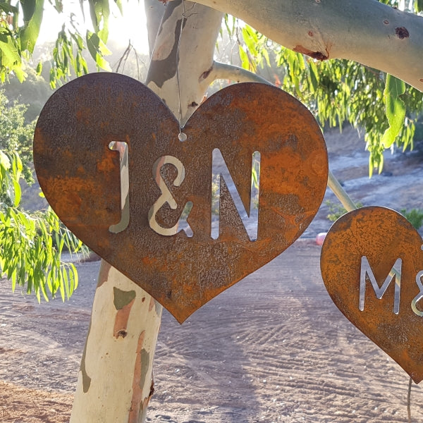 Image of a rusty metal heart with the initials 'J & N' hanging from a gum tree.